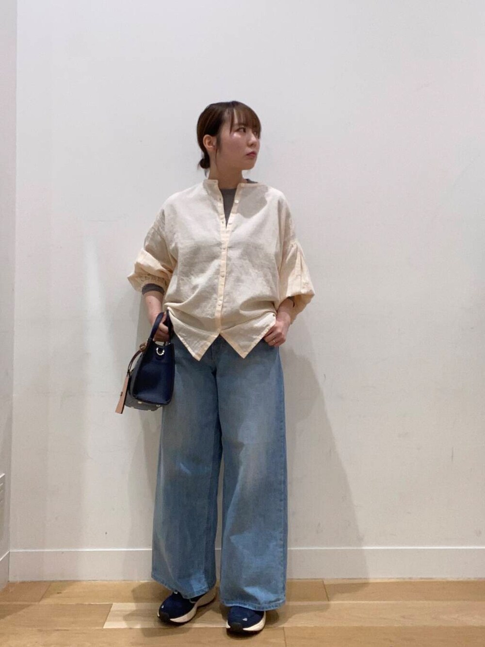 ブルー系のスニーカー、ブルー系のハンドバッグ、ブルー系のデニムパンツを着用したレディースの冬コーディネートの2枚目の写真
