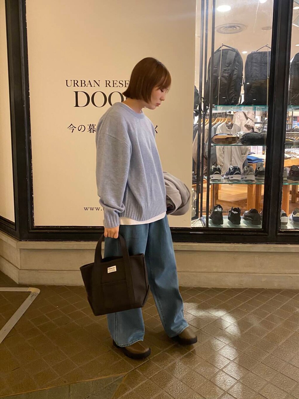 ブルー系のニット/セーター、ブラウン系のブーツ、グレー系のトートバッグを着用したレディースの冬コーディネートの3枚目の写真