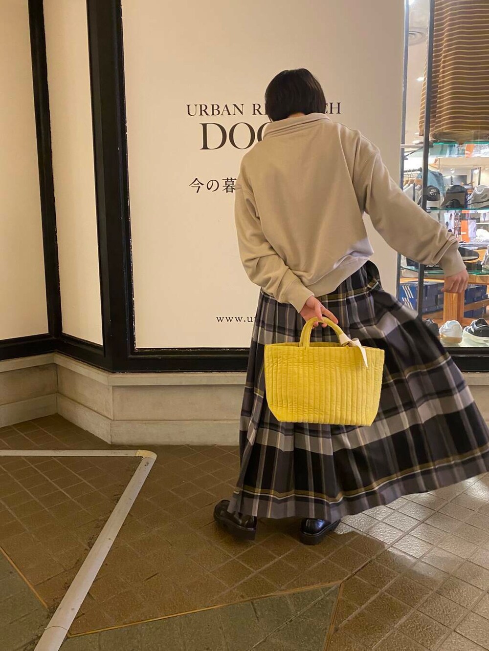 イエロー系のトートバッグ、ベージュ系のスウェット、ブルー系のスカートを着用したレディースの秋コーディネートの3枚目の写真