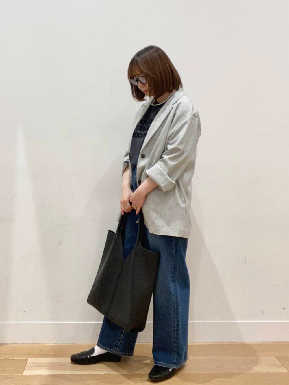 ブラック系のローファー、ブルー系のデニムパンツ、ブラック系のトートバッグを着用したレディースの春コーディネートの3枚目の写真