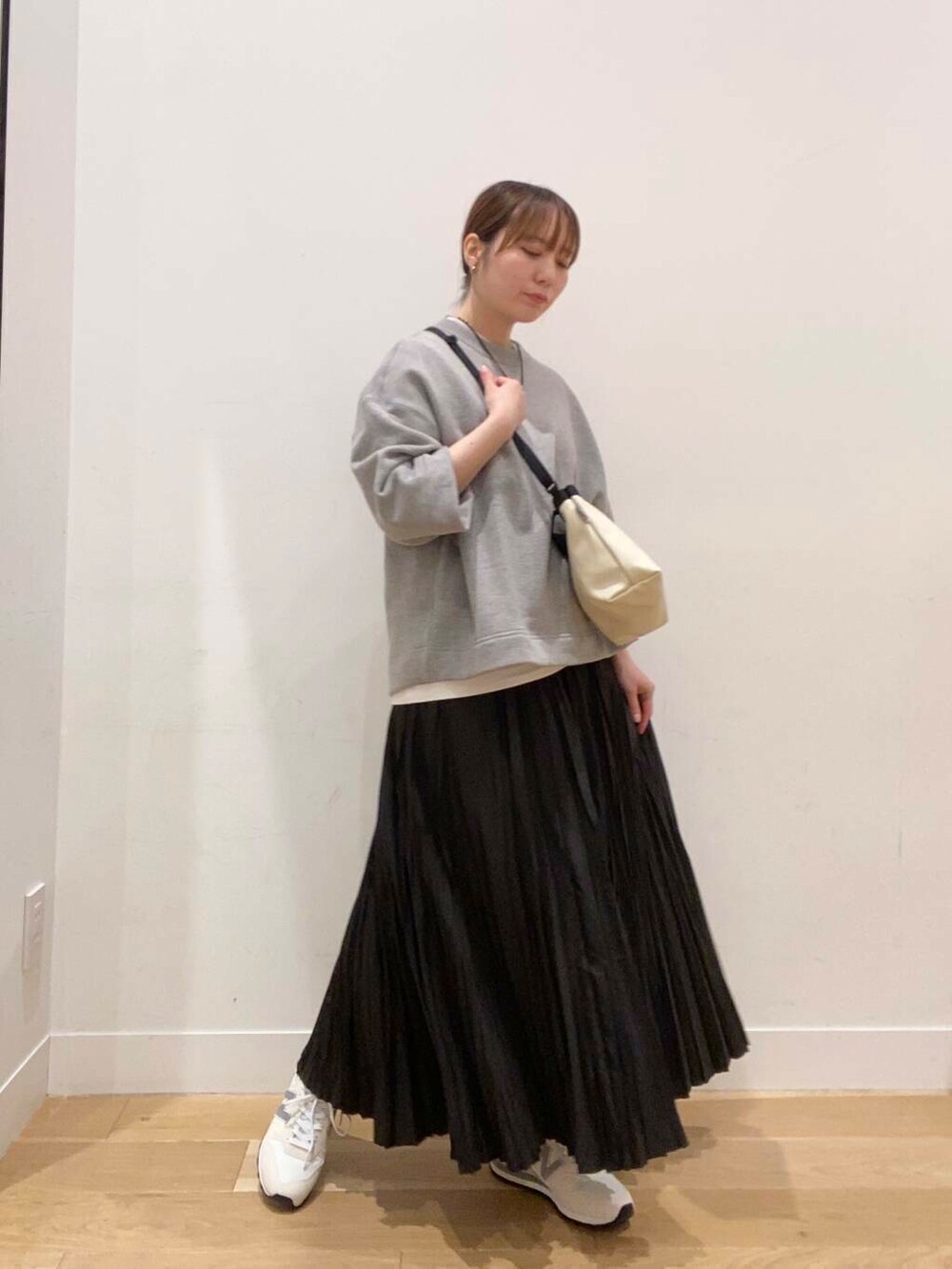 ブラック系のスカート、ベージュ系のスニーカー、グレー系のスウェットを着用したレディースの春コーディネートの2枚目の写真