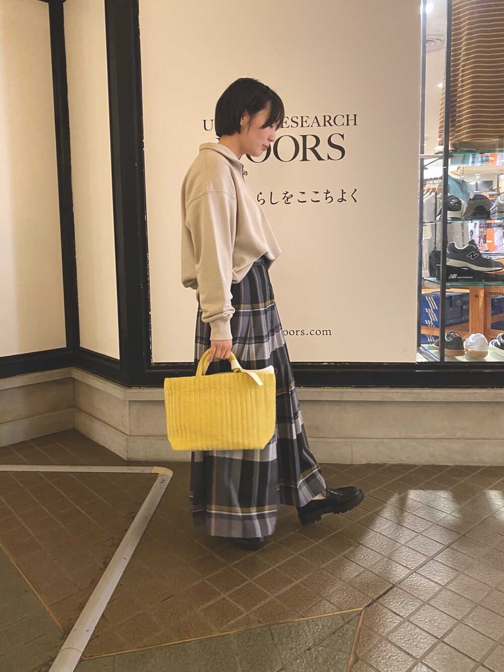 イエロー系のトートバッグ、ブラック系のスカート、ベージュ系のスウェットを着用したレディースの秋コーディネートの3枚目の写真