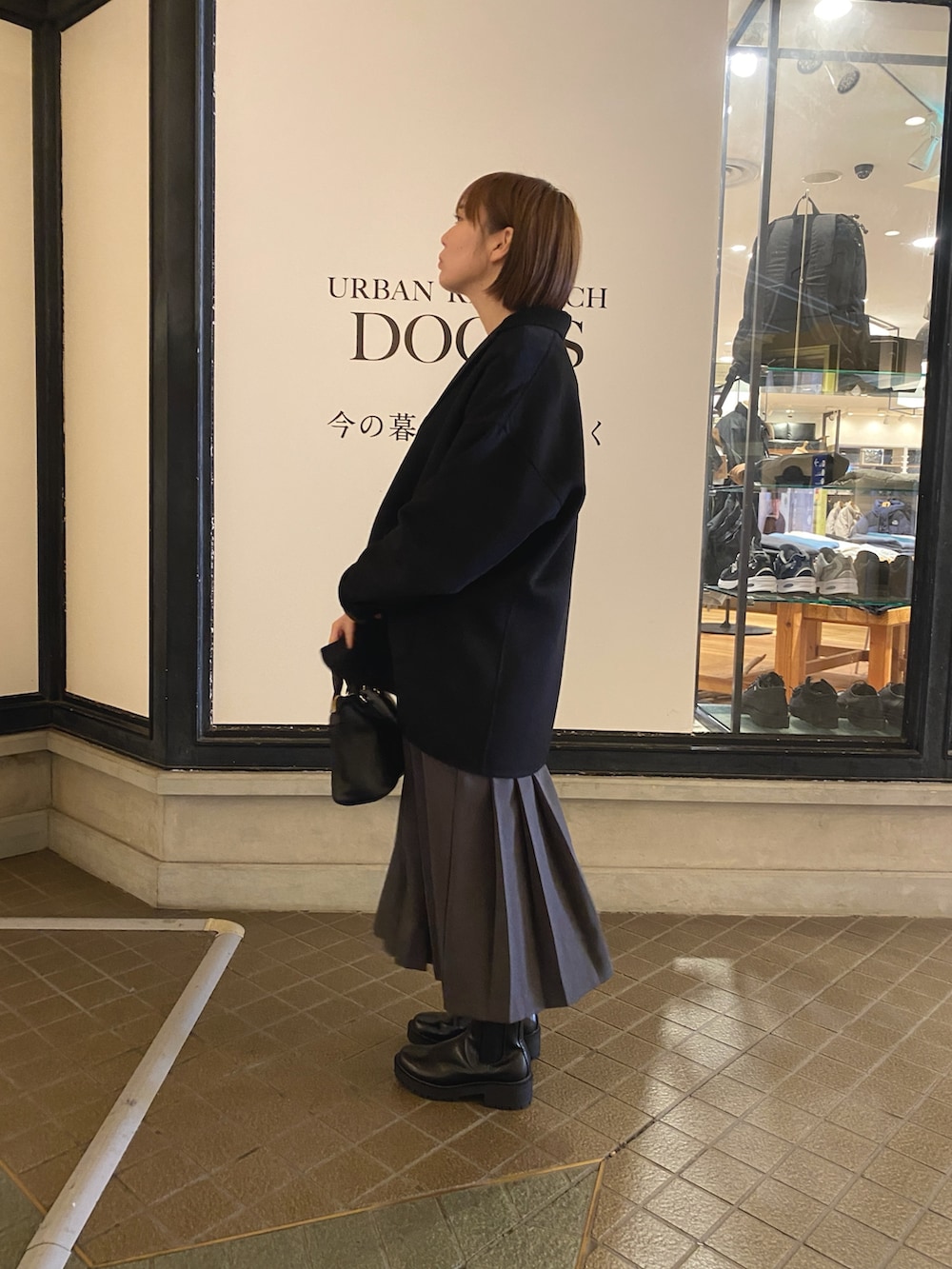 グレー系のワンピース、ブラック系のその他アウター、ブラック系のブーツを着用したレディースの秋コーディネートの3枚目の写真