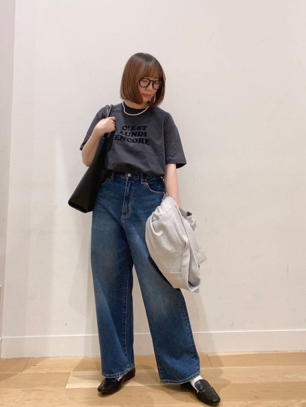 ブラック系のローファー、ブルー系のデニムパンツ、ブラック系のトートバッグを着用したレディースの春コーディネートの2枚目の写真