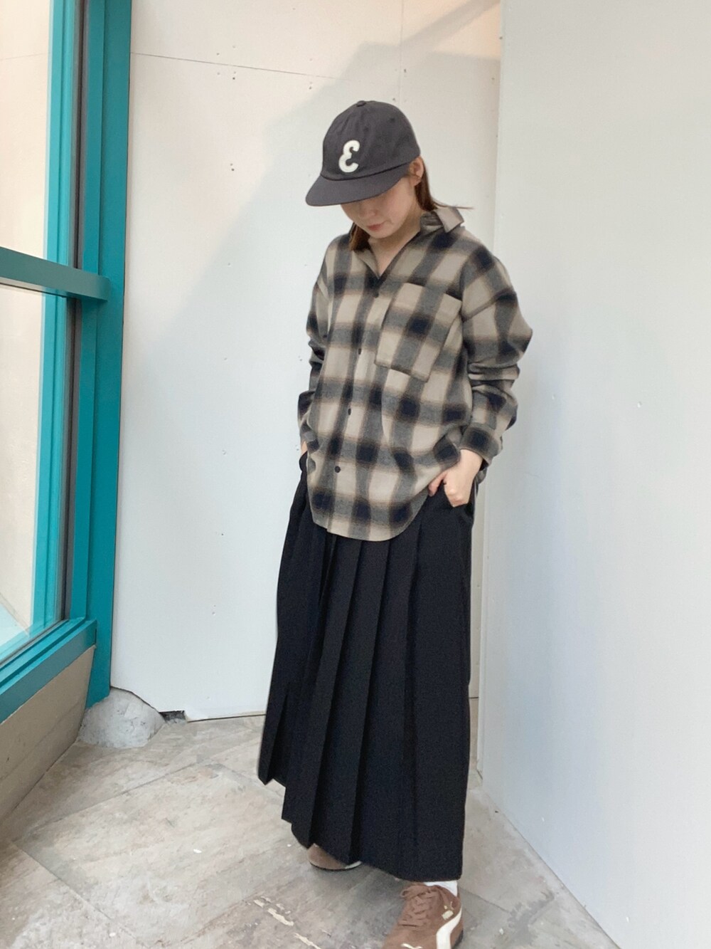 ブラック系のスカート、ベージュ系のシャツ/ブラウス、グレー系のキャップを着用したレディースの秋コーディネートの2枚目の写真