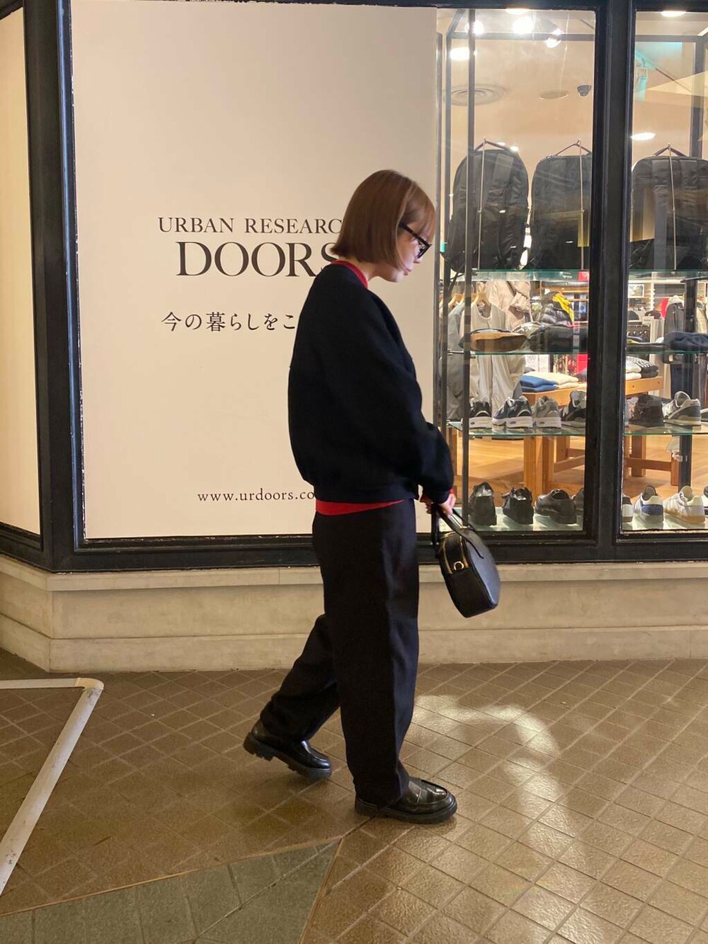 レッド系のニット/セーター、ブラック系のショルダーバッグ、ブラック系のカーディガン/ボレロを着用したレディースの秋コーディネートの4枚目の写真