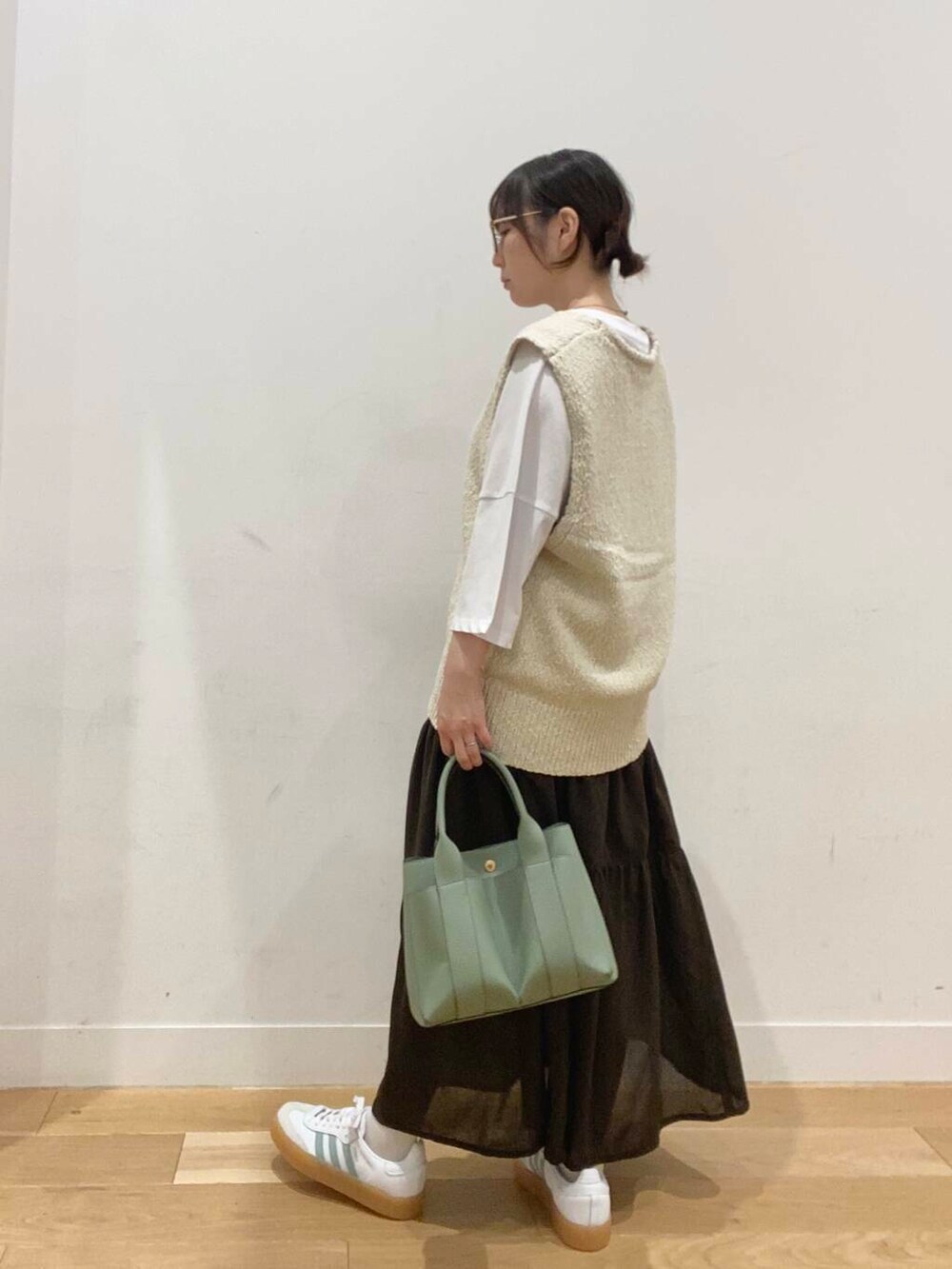 グリーン系のトートバッグ、ホワイト系のTシャツ/カットソー、ブラウン系のスカートを着用したレディースの夏コーディネートの3枚目の写真