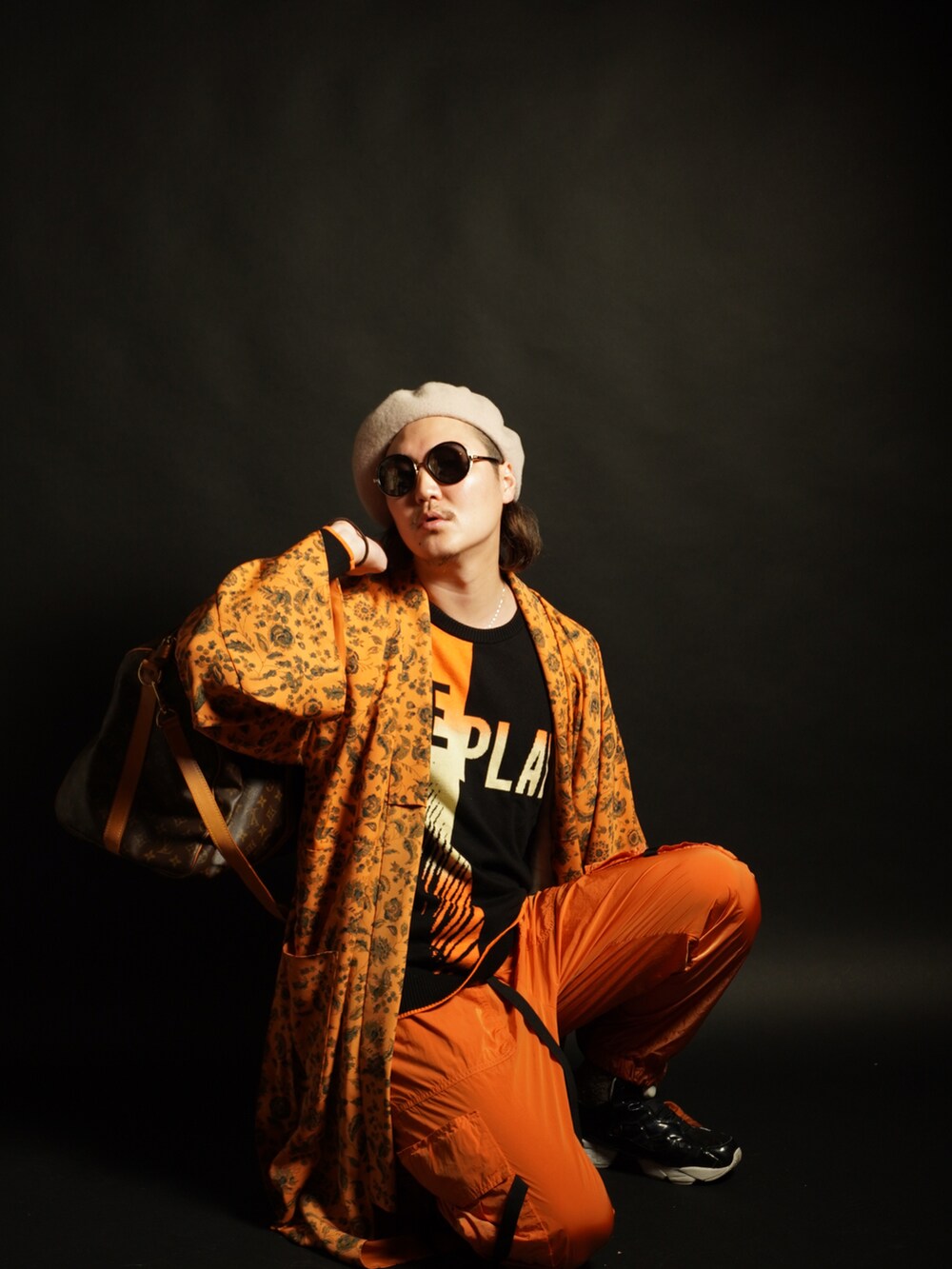 ブラウン系のボストンバッグ、オレンジ系のその他パンツ、ホワイト系のスニーカーを着用したメンズの冬コーディネートの2枚目の写真