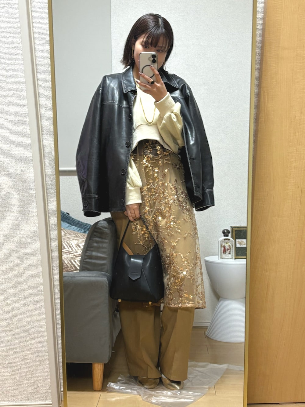 ベージュ系のスラックス、ゴールド系のスカート、ゴールド系のサンダルを着用したレディースの冬コーディネートの2枚目の写真