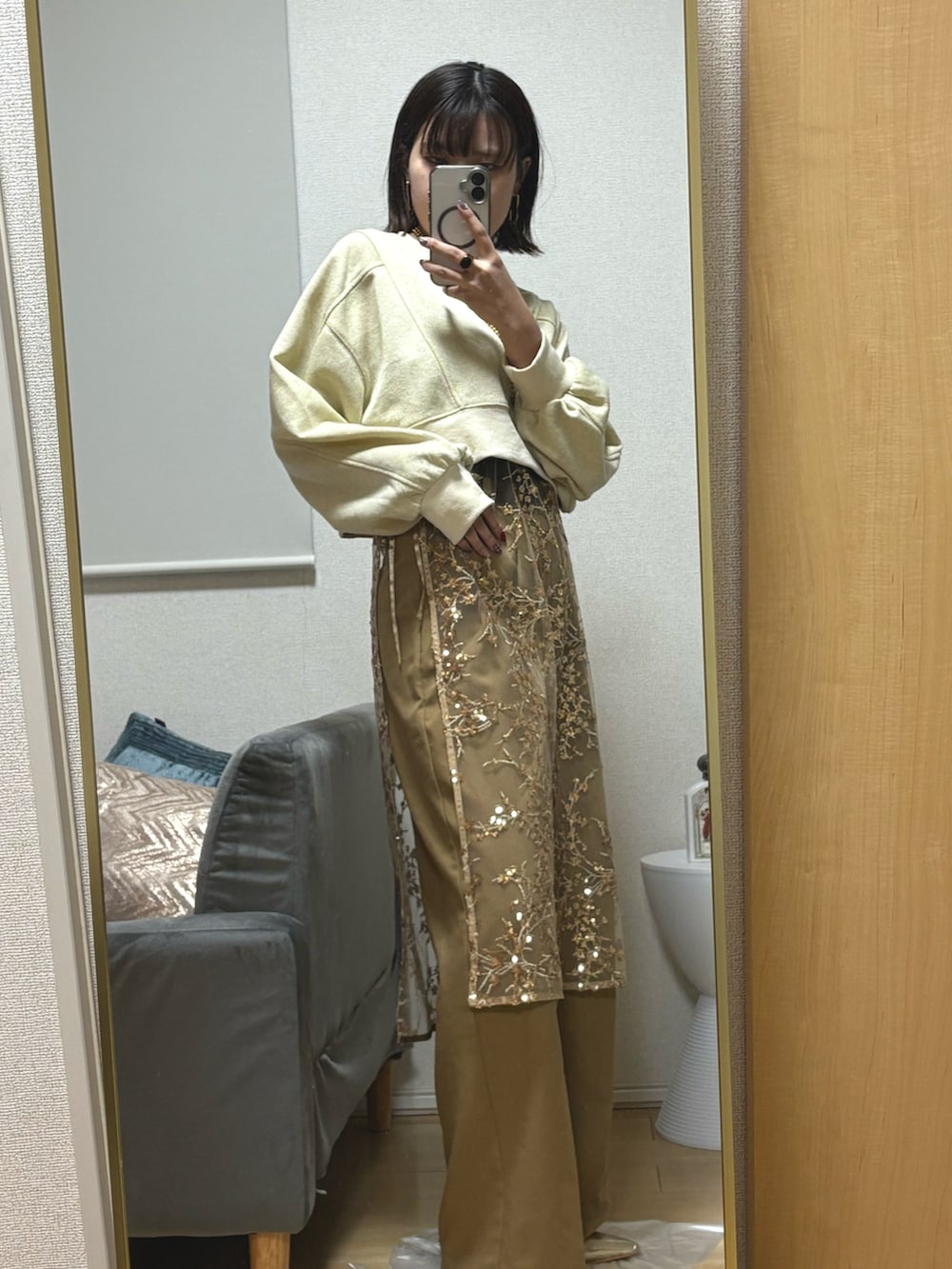 ベージュ系のスラックス、ゴールド系のスカート、ゴールド系のサンダルを着用したレディースの冬コーディネートの3枚目の写真
