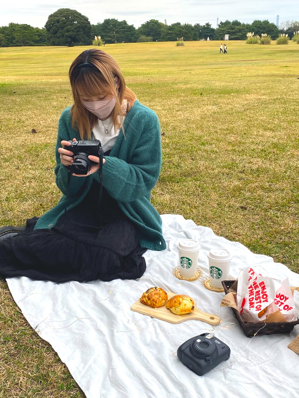 グリーン系のカーディガン/ボレロ、ブラック系のワンピース、ブラック系のブーツを着用したレディースの秋コーディネートの2枚目の写真