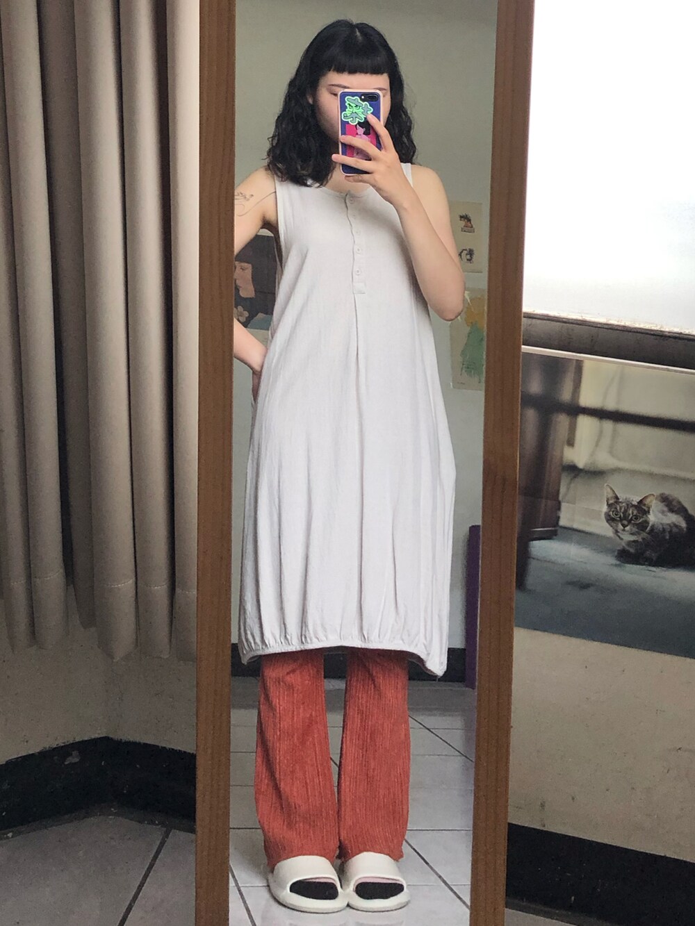 ブラック系のノーカラージャケット、ホワイト系のジャンパースカート、オレンジ系のチノパンツを着用したレディースの夏コーディネートの2枚目の写真