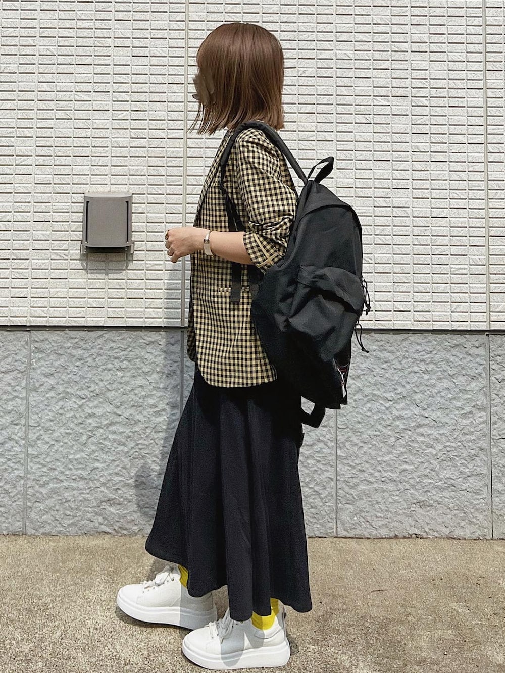 ブラック系のバックパック/リュック、ホワイト系のスニーカー、イエロー系のジャケット/アウターを着用したレディースの春コーディネートの3枚目の写真