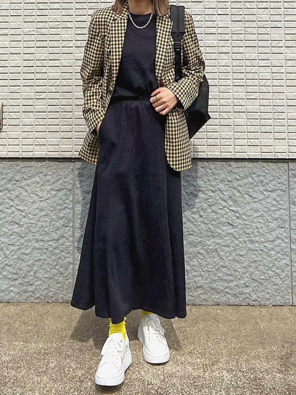 ブラック系のバックパック/リュック、ホワイト系のスニーカー、イエロー系のジャケット/アウターを着用したレディースの春コーディネートの2枚目の写真