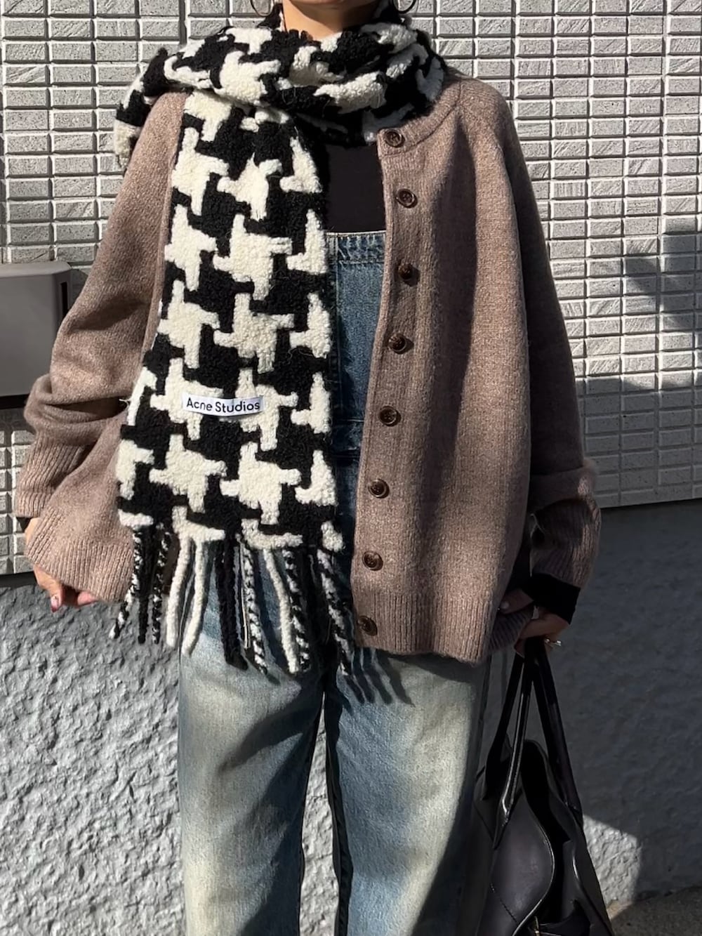 ベージュ系のカーディガン/ボレロ、ブルー系のサロペット/オーバーオール、ブラック系のブーツを着用したレディースの冬コーディネートの4枚目の写真