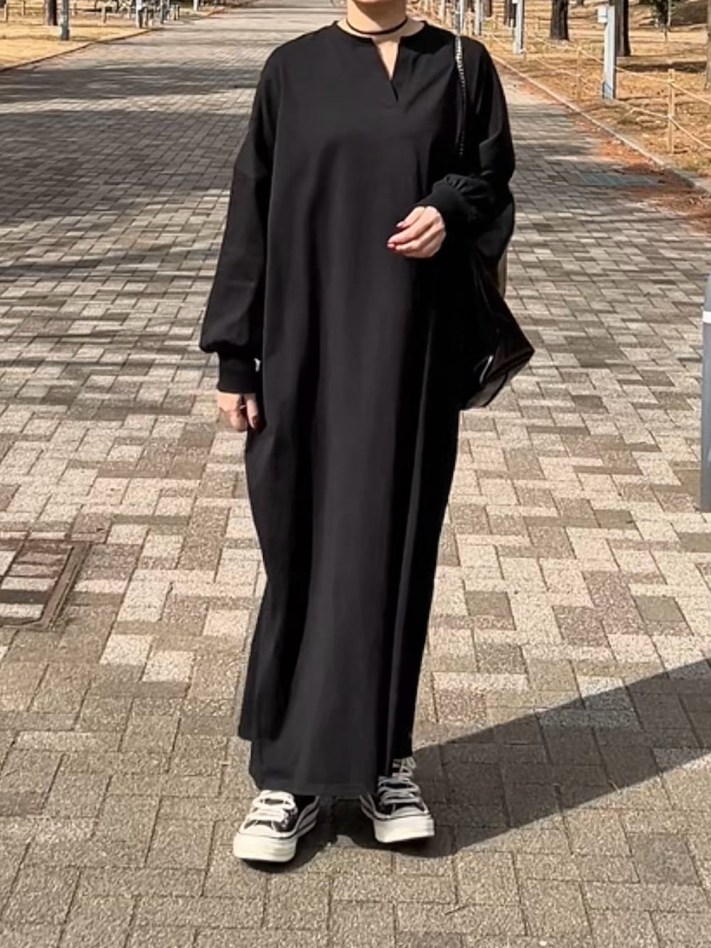 ブラック系のスニーカー、ブラック系のワンピース、ブルー系のデニムジャケットを着用したレディースの冬コーディネートの3枚目の写真