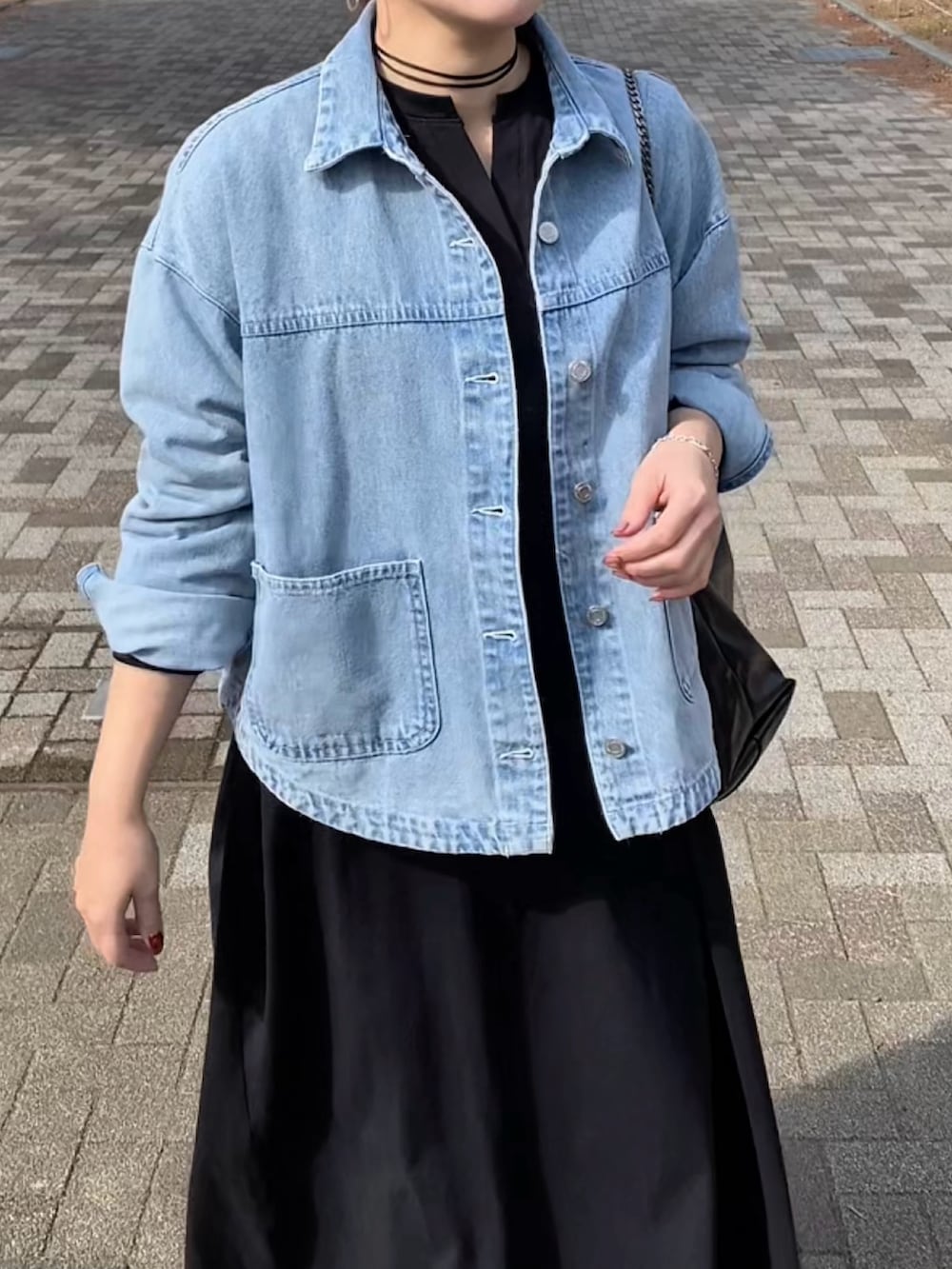 ブラック系のスニーカー、ブラック系のワンピース、ブルー系のデニムジャケットを着用したレディースの冬コーディネートの5枚目の写真