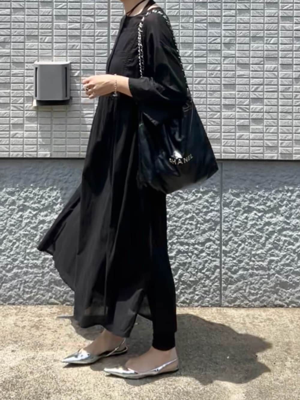 ブラック系のワンピース、シルバー系のパンプス、ブラック系のショルダーバッグを着用したレディースの夏コーディネートの2枚目の写真