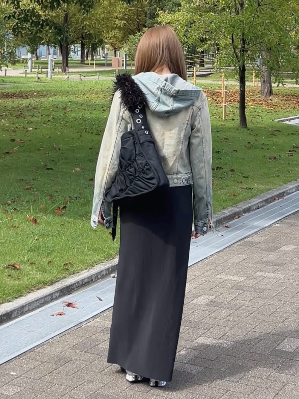 ブルー系のデニムジャケット、ブラック系のショルダーバッグ、ホワイト系のトップスを着用したレディースの秋コーディネートの4枚目の写真