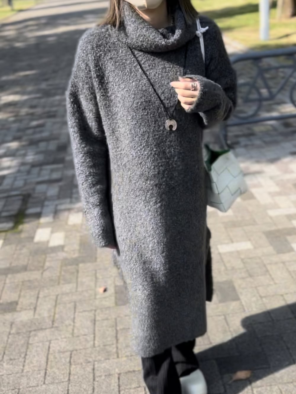 グレー系のワンピース、ブラック系のパンツ、ホワイト系のショルダーバッグを着用したレディースの秋コーディネートの3枚目の写真