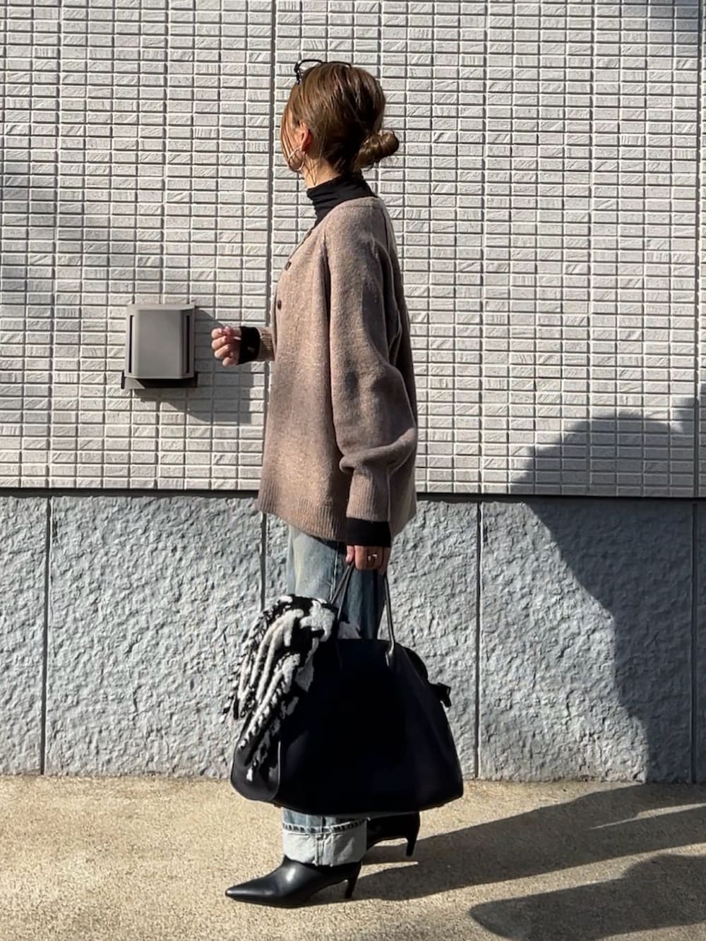 ベージュ系のカーディガン/ボレロ、ブルー系のサロペット/オーバーオール、ブラック系のブーツを着用したレディースの冬コーディネートの2枚目の写真