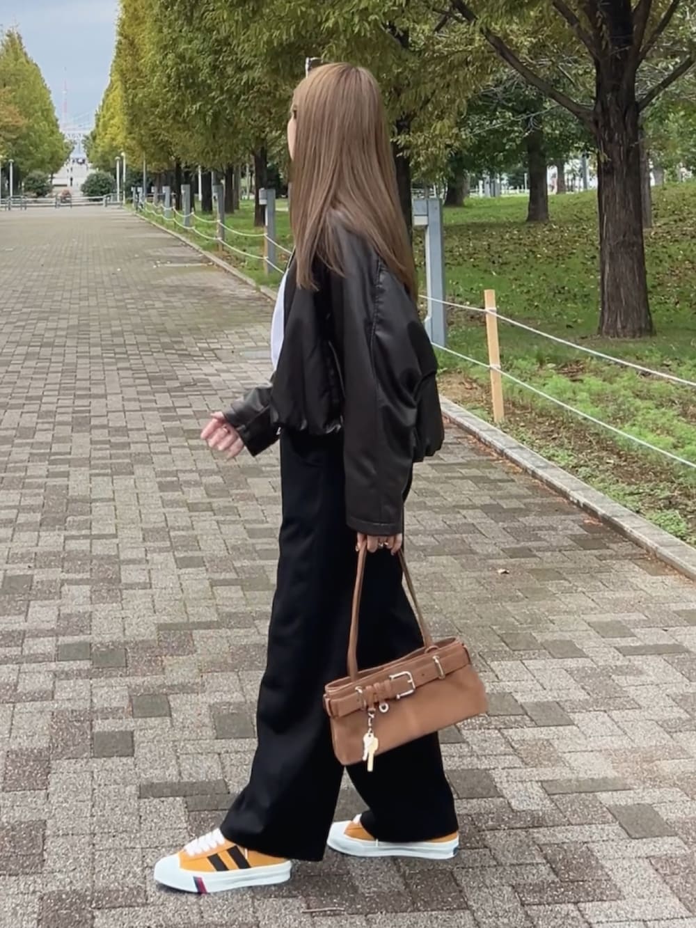 イエロー系のスニーカー、ブラウン系のショルダーバッグ、ブラック系のスウェットパンツを着用したレディースの秋コーディネートの4枚目の写真