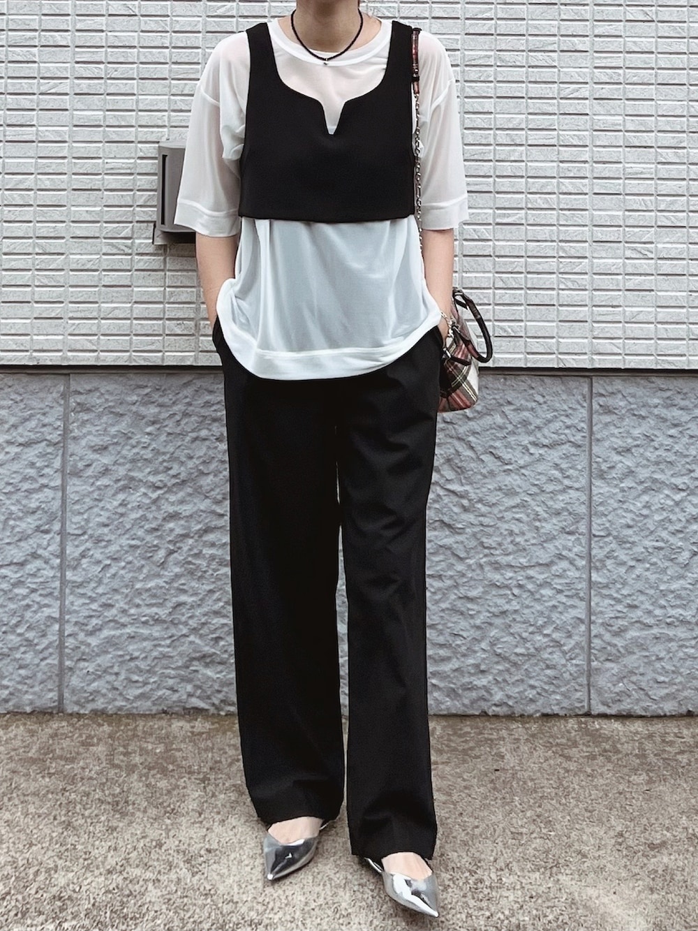 ホワイト系のTシャツ/カットソー、ブラック系のベスト、ブラック系のパンツを着用したレディースの夏コーディネートの3枚目の写真
