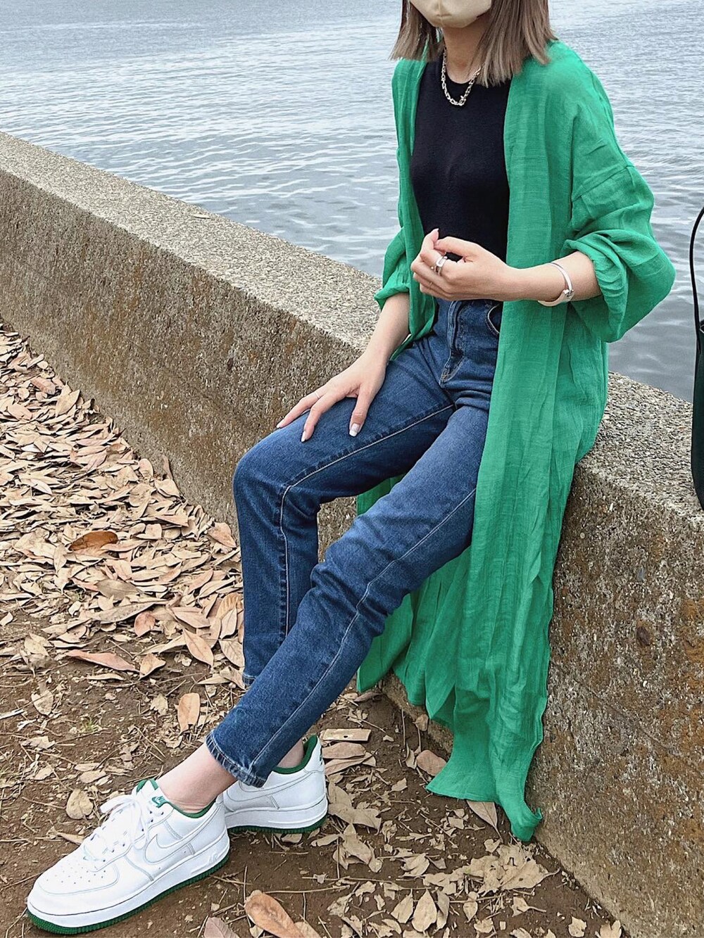 グリーン系のカーディガン/ボレロ、ブラック系のニット/セーター、ブルー系のデニムパンツを着用したレディースの春コーディネートの2枚目の写真