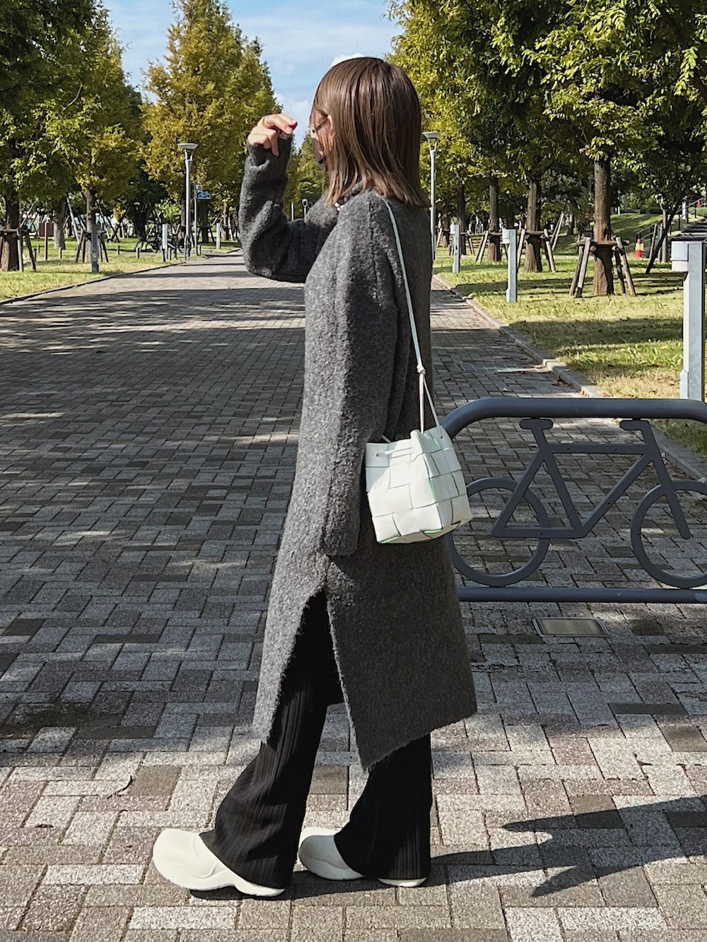 グレー系のワンピース、ブラック系のパンツ、ホワイト系のショルダーバッグを着用したレディースの秋コーディネートの2枚目の写真