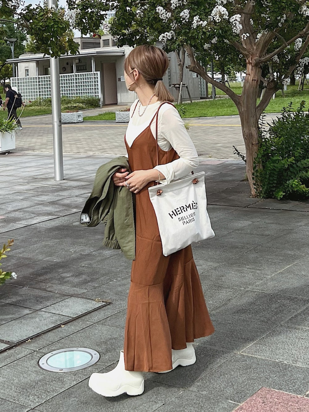 グリーン系のノーカラージャケット、ブラウン系のワンピース、ベージュ系のトートバッグを着用したレディースの秋コーディネートの2枚目の写真