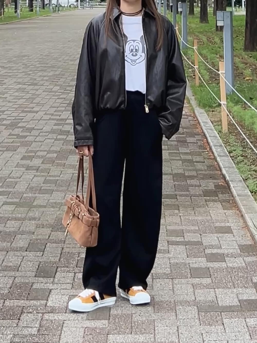 イエロー系のスニーカー、ブラウン系のショルダーバッグ、ブラック系のスウェットパンツを着用したレディースの秋コーディネートの2枚目の写真