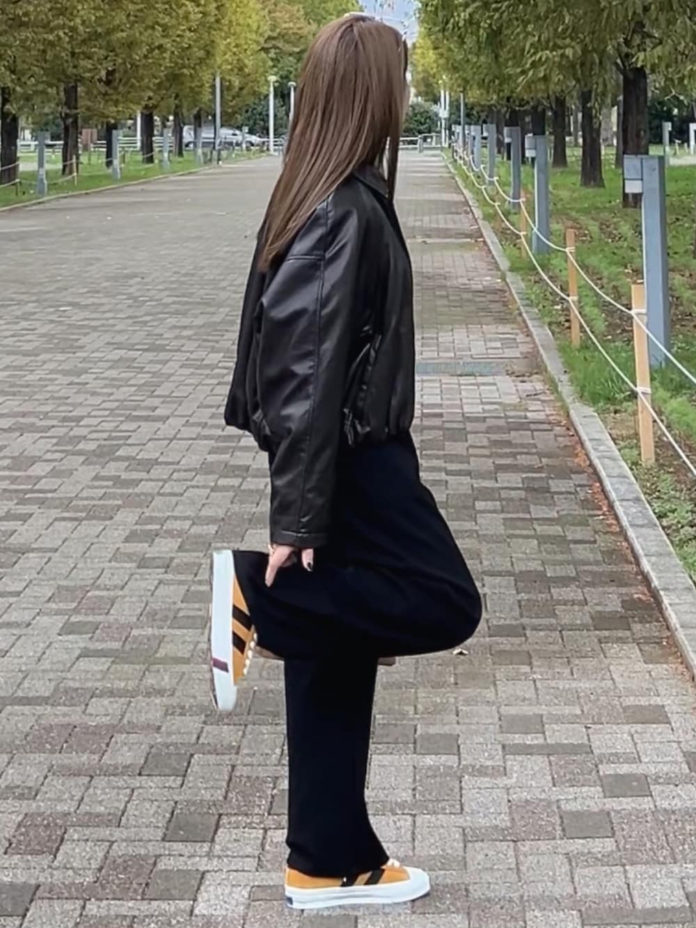 イエロー系のスニーカー、ブラウン系のショルダーバッグ、ブラック系のスウェットパンツを着用したレディースの秋コーディネートの3枚目の写真