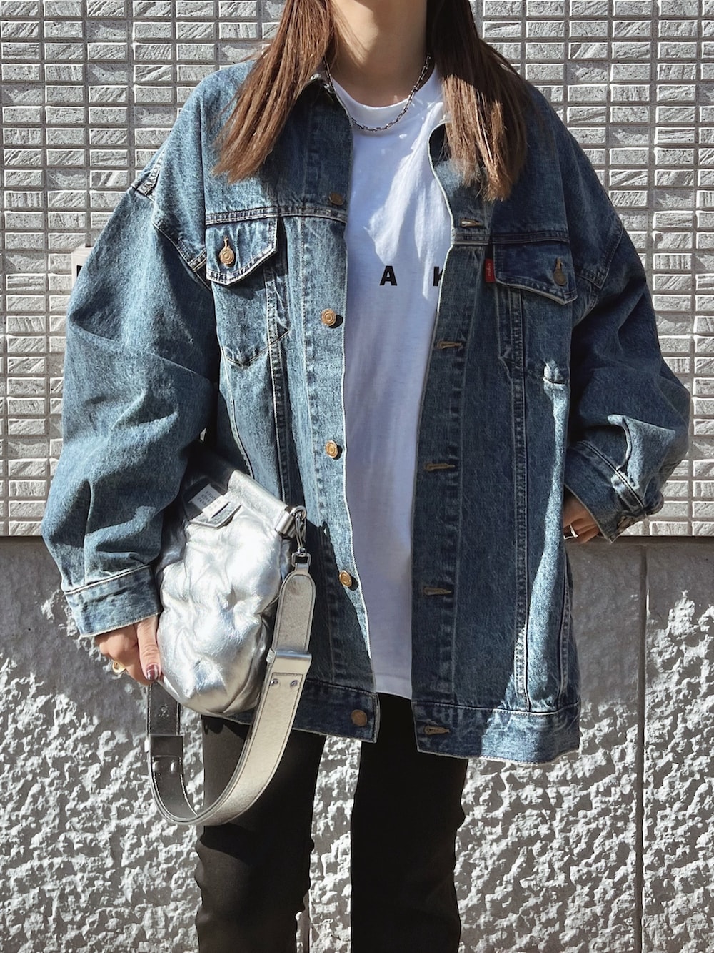 ブルー系のデニムジャケット、ホワイト系のTシャツ/カットソー、ホワイト系のスニーカーを着用したレディースの冬コーディネートの3枚目の写真