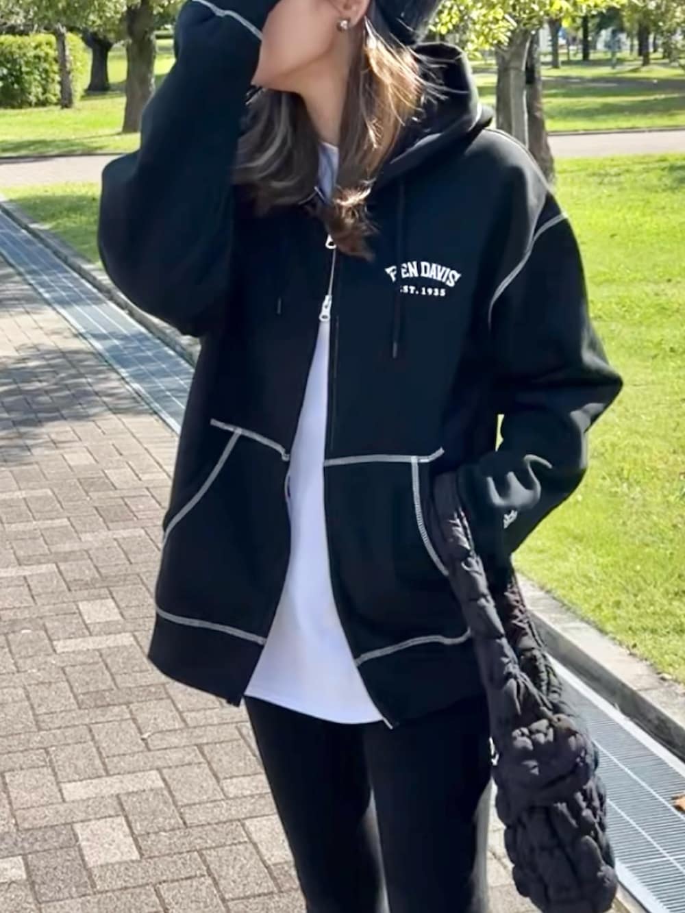 ブラック系のパーカー、ブラック系のブーツ、ブラック系のショルダーバッグを着用したレディースの秋コーディネートの3枚目の写真