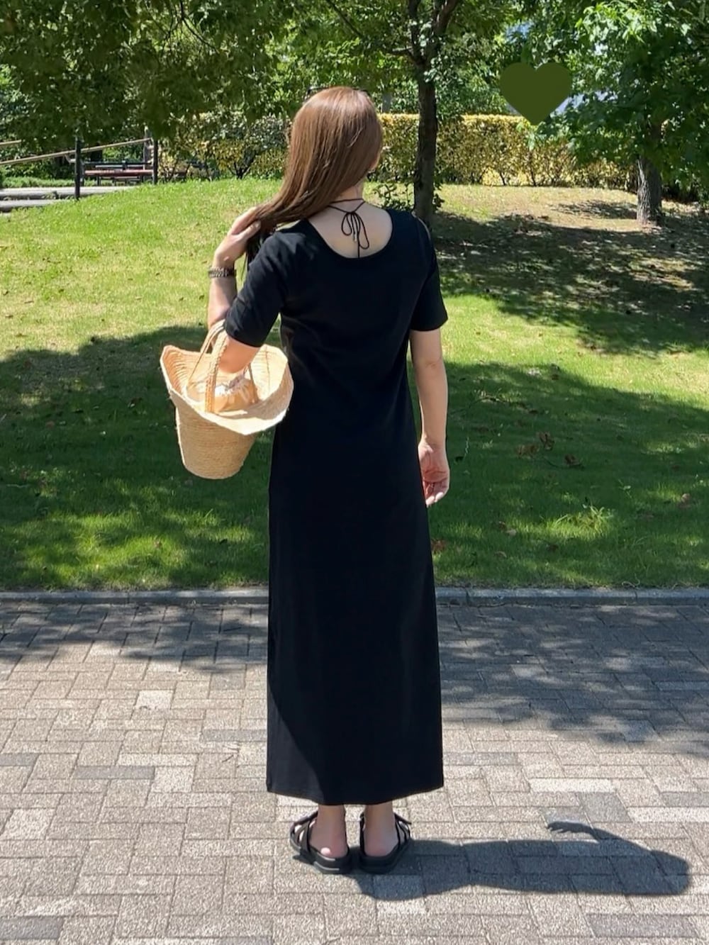 ブラック系のワンピース、ベージュ系のかごバッグ、ブラック系のサンダルを着用したレディースの夏コーディネートの2枚目の写真