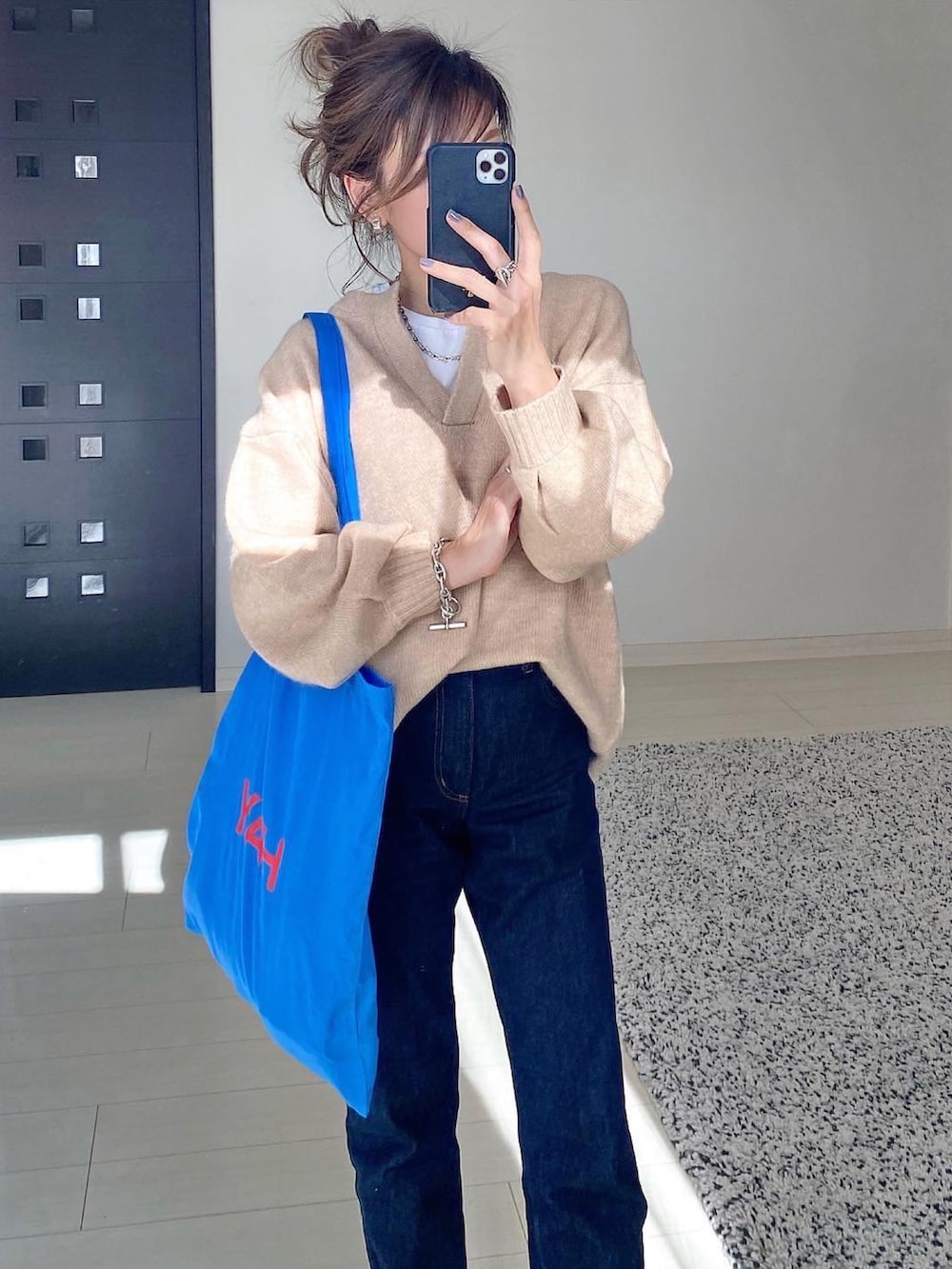 ベージュ系のニット/セーター、ブルー系のデニムパンツ、ブルー系のバッグを着用したレディースの秋コーディネートの2枚目の写真