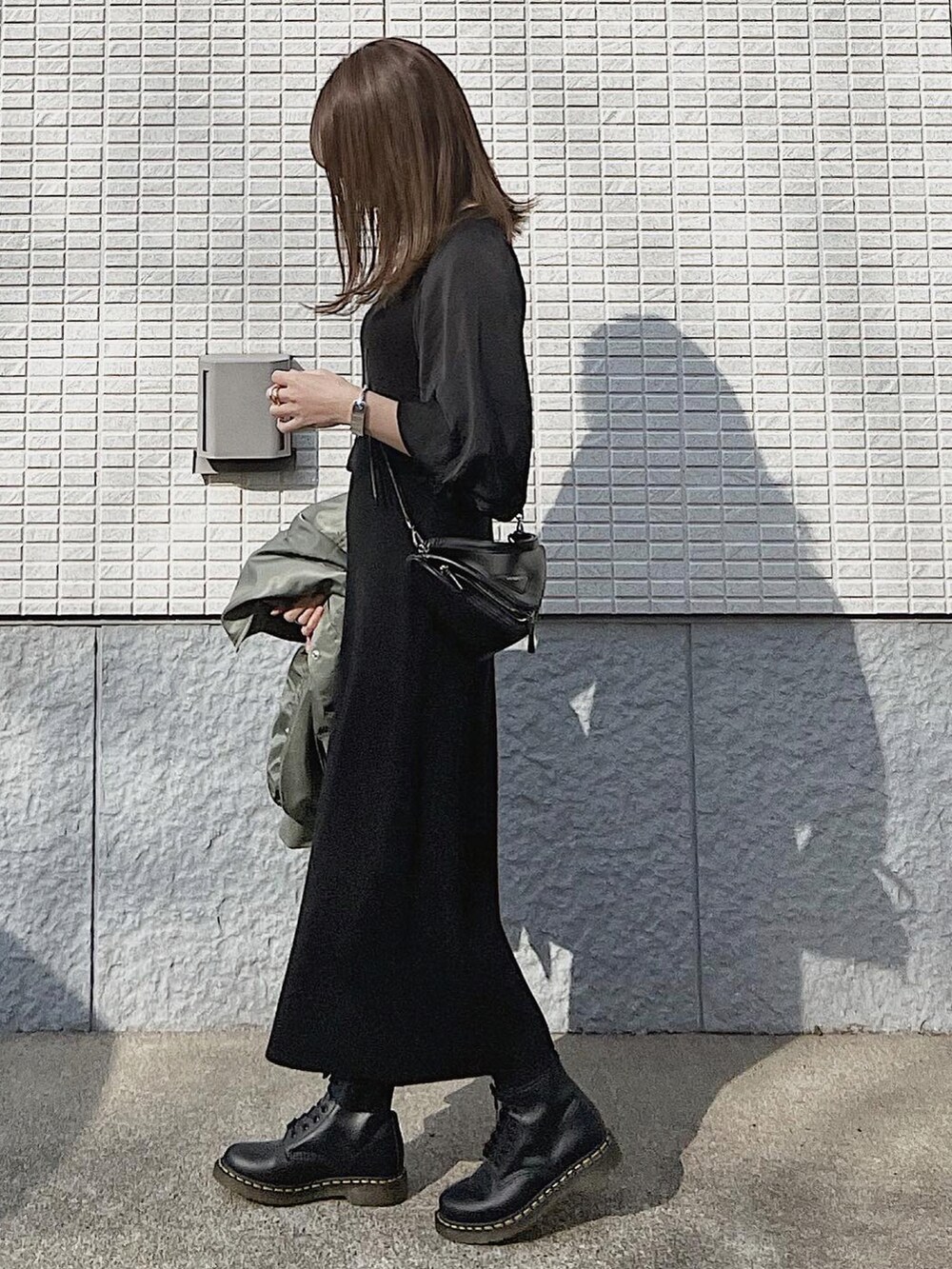 ブラック系のワンピース、グリーン系のMA-1、ブラック系のブーツを着用したレディースの冬コーディネートの3枚目の写真