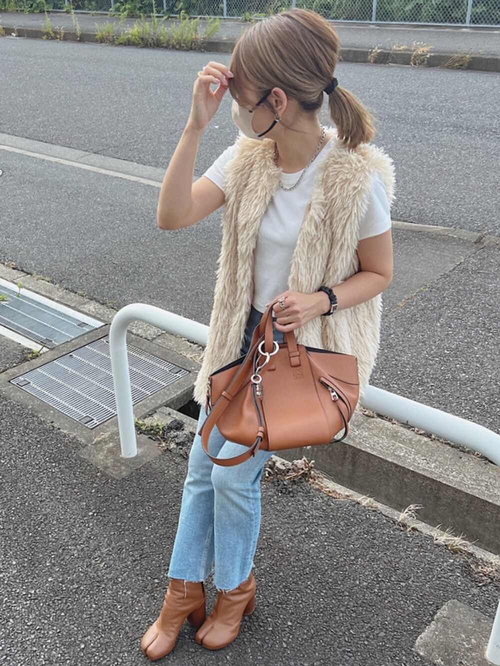 ホワイト系のベスト、ブラウン系のハンドバッグ、ブラウン系のブーツを着用したレディースの夏コーディネートの2枚目の写真