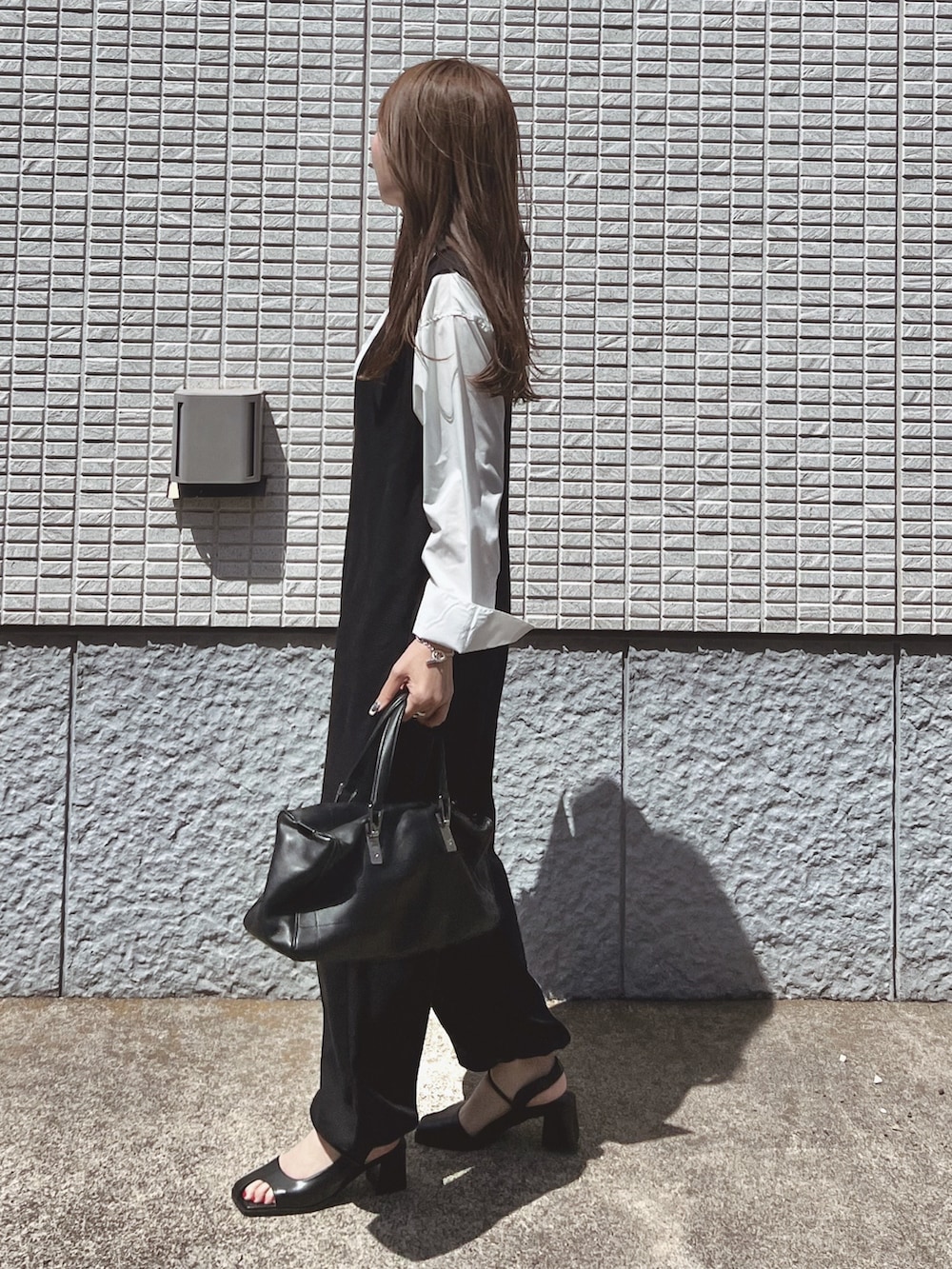 ブラック系のサロペット/オーバーオール、ホワイト系のシャツ/ブラウス、ブラック系のバッグを着用したレディースの春コーディネートの5枚目の写真