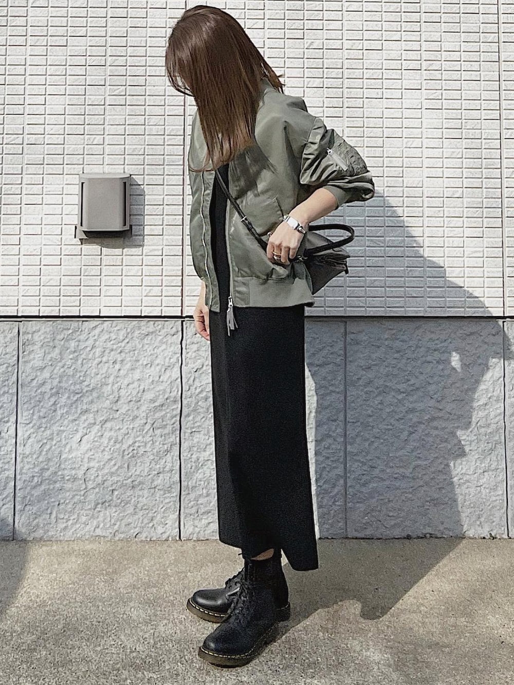 ブラック系のワンピース、グリーン系のMA-1、ブラック系のブーツを着用したレディースの冬コーディネートの4枚目の写真