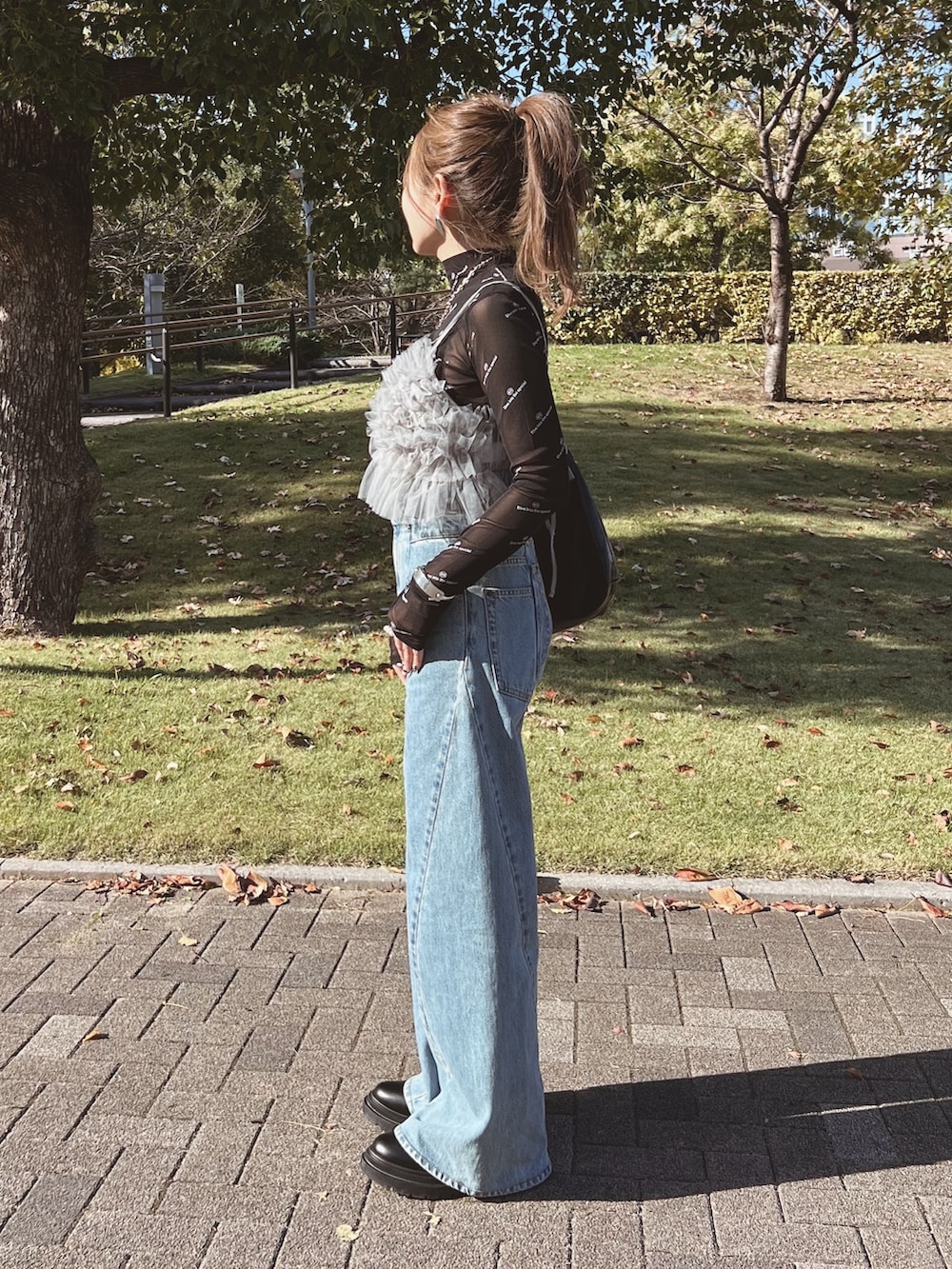 グレー系のキャミソール、ブラック系のTシャツ/カットソー、ブルー系のデニムパンツを着用したレディースの秋コーディネートの4枚目の写真