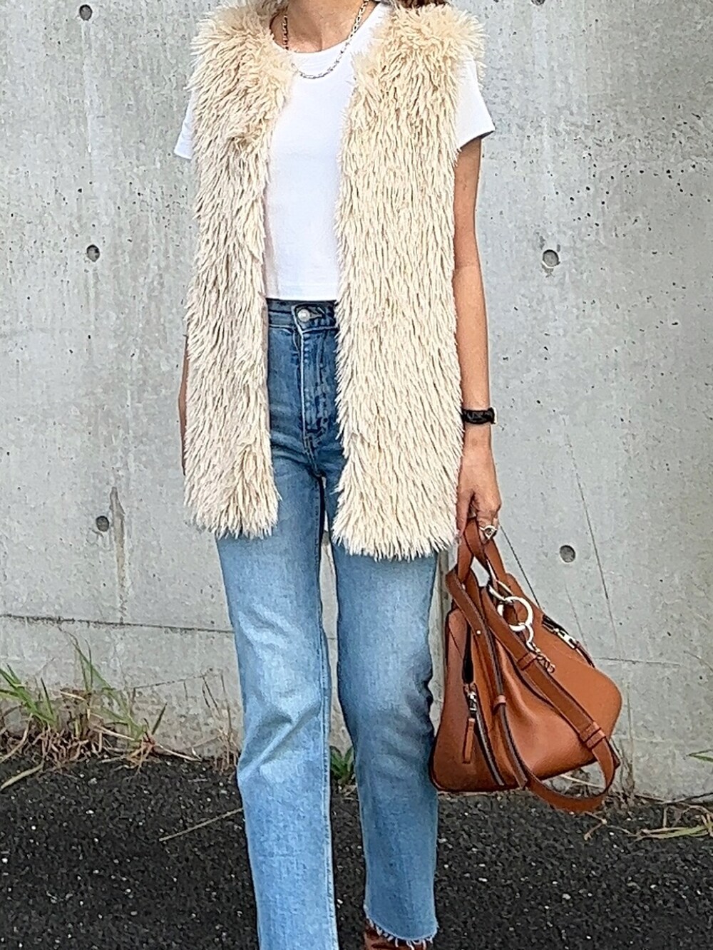 ホワイト系のベスト、ブラウン系のハンドバッグ、ブラウン系のブーツを着用したレディースの夏コーディネートの3枚目の写真