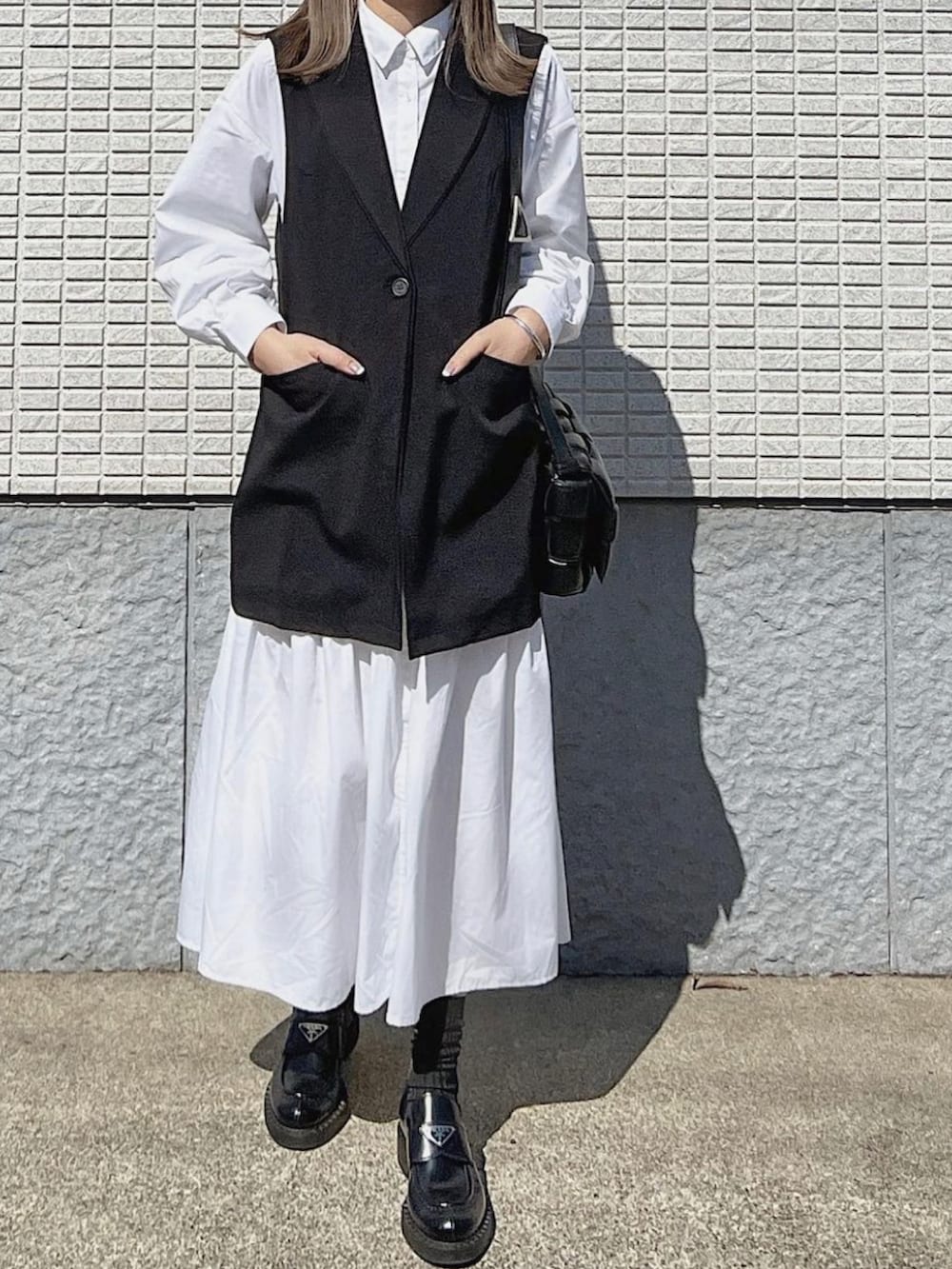 ブラック系のベスト、ブラック系のバッグ、ブラック系のブーツを着用したレディースの春コーディネートの3枚目の写真