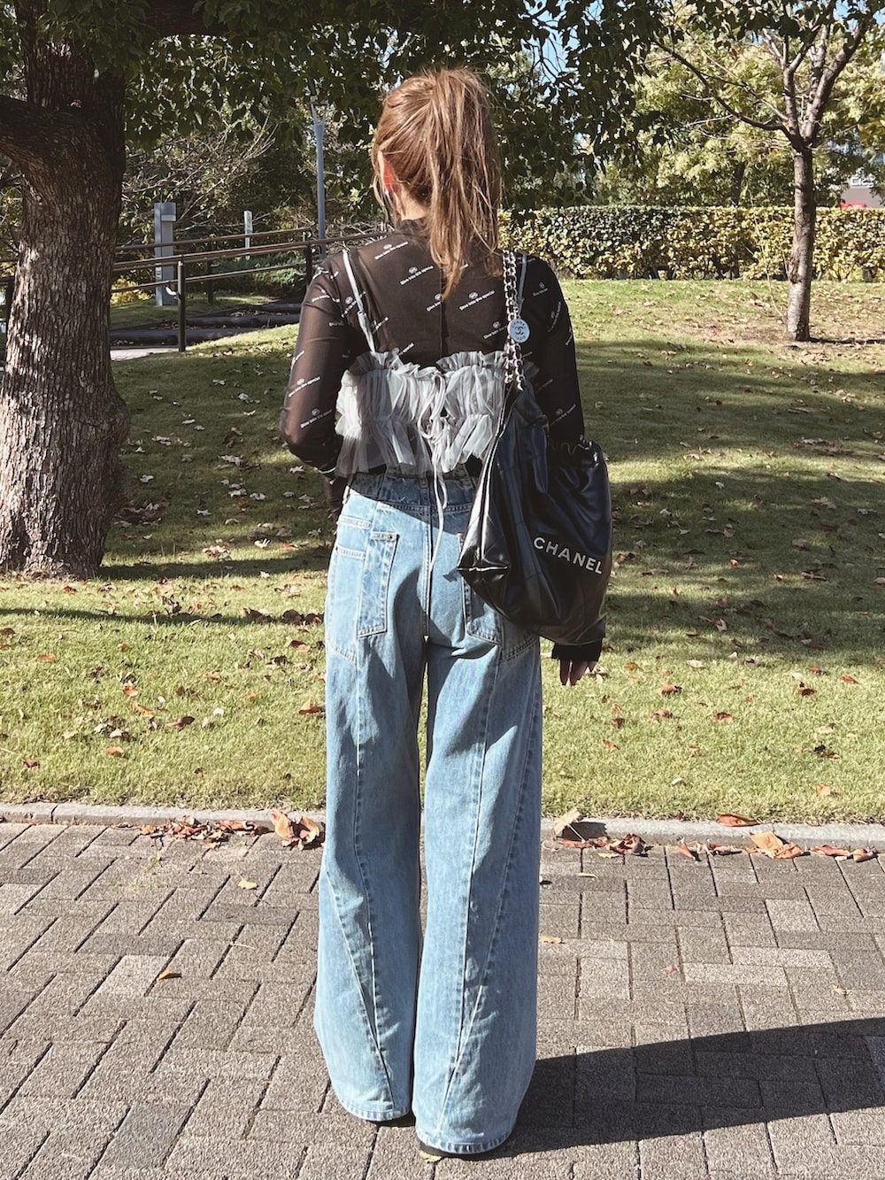 グレー系のキャミソール、ブラック系のTシャツ/カットソー、ブルー系のデニムパンツを着用したレディースの秋コーディネートの3枚目の写真