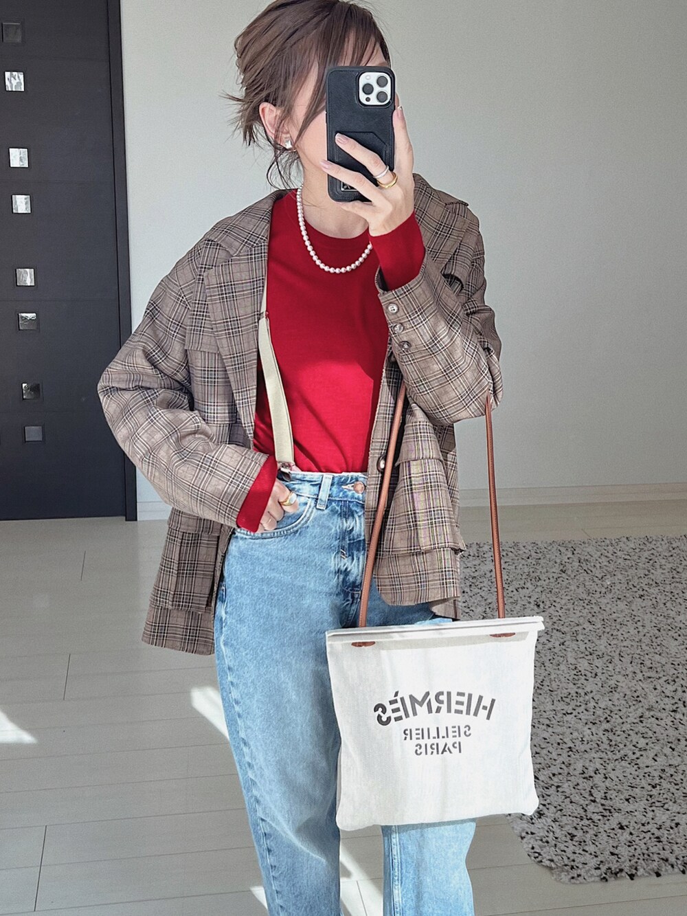 ブラウン系のテーラードジャケット、ブルー系のデニムパンツ、レッド系のニット/セーターを着用したレディースの秋コーディネートの2枚目の写真