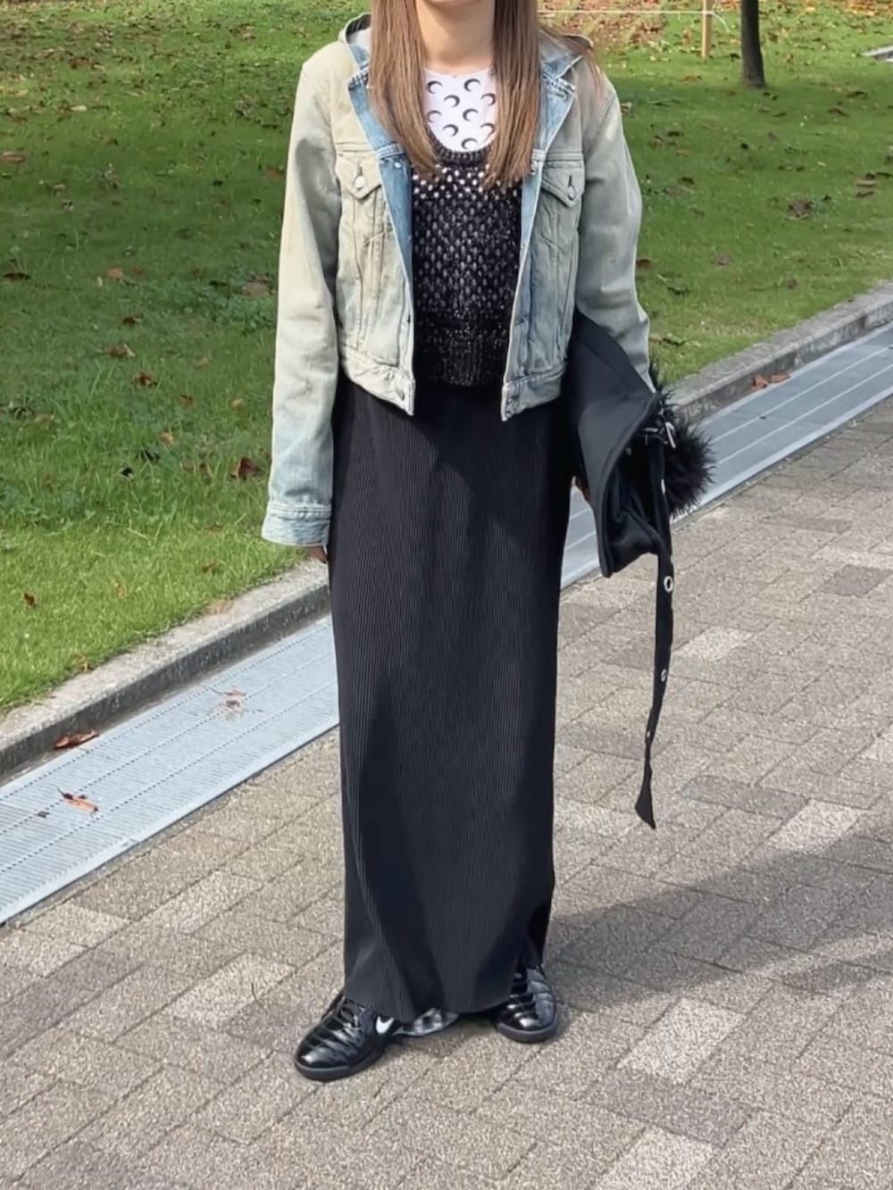 ブルー系のデニムジャケット、ブラック系のショルダーバッグ、ホワイト系のトップスを着用したレディースの秋コーディネートの2枚目の写真