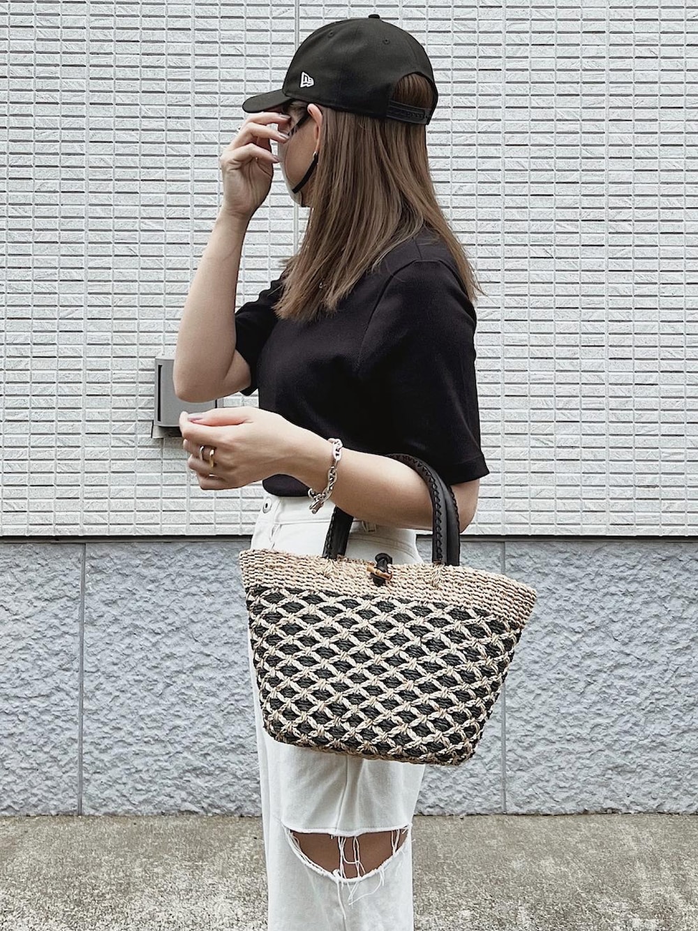 ベージュ系のかごバッグ、ホワイト系のパンツ、ブラック系のTシャツ/カットソーを着用したレディースの夏コーディネートの3枚目の写真