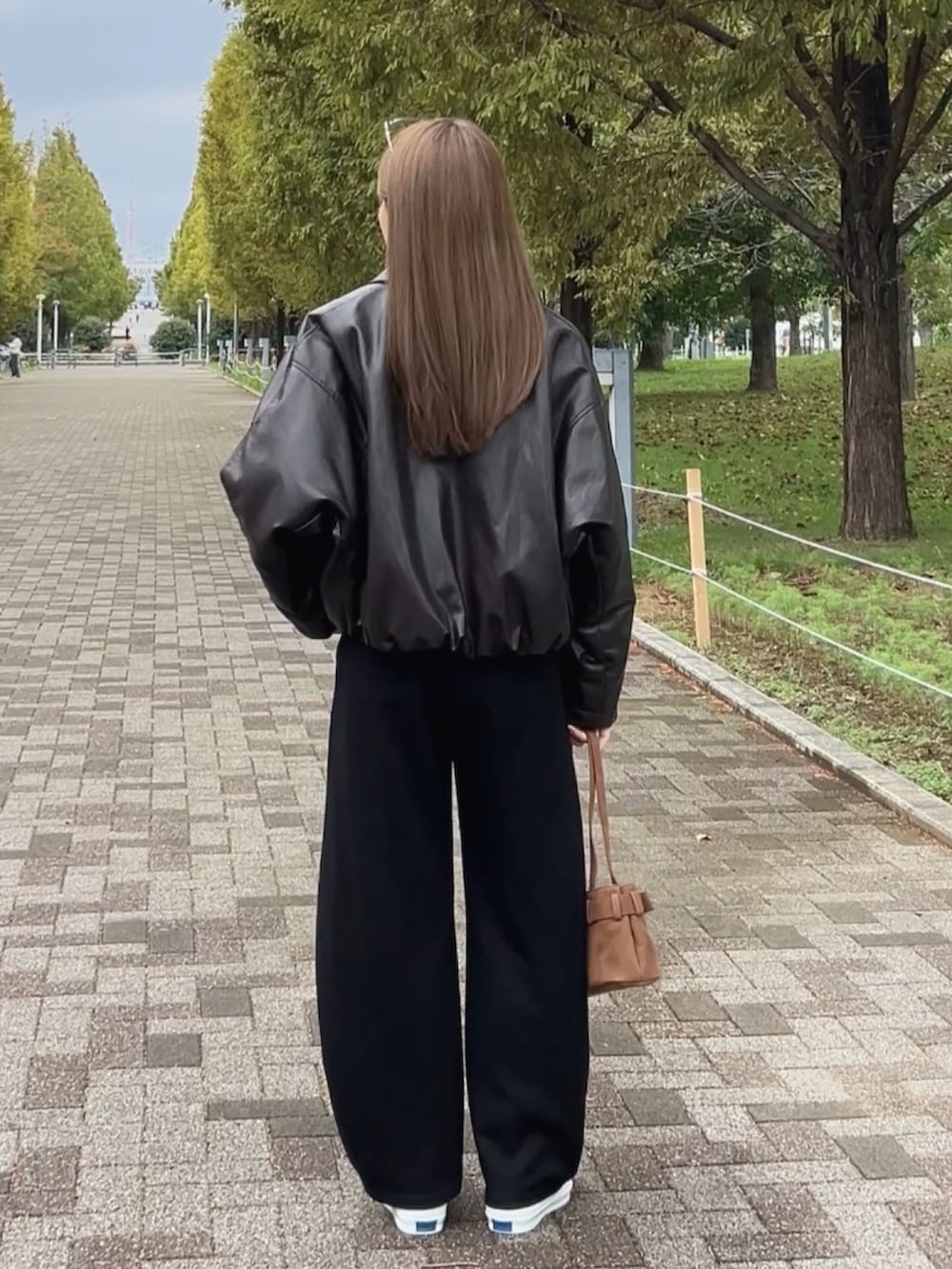 イエロー系のスニーカー、ブラウン系のショルダーバッグ、ブラック系のスウェットパンツを着用したレディースの秋コーディネートの5枚目の写真