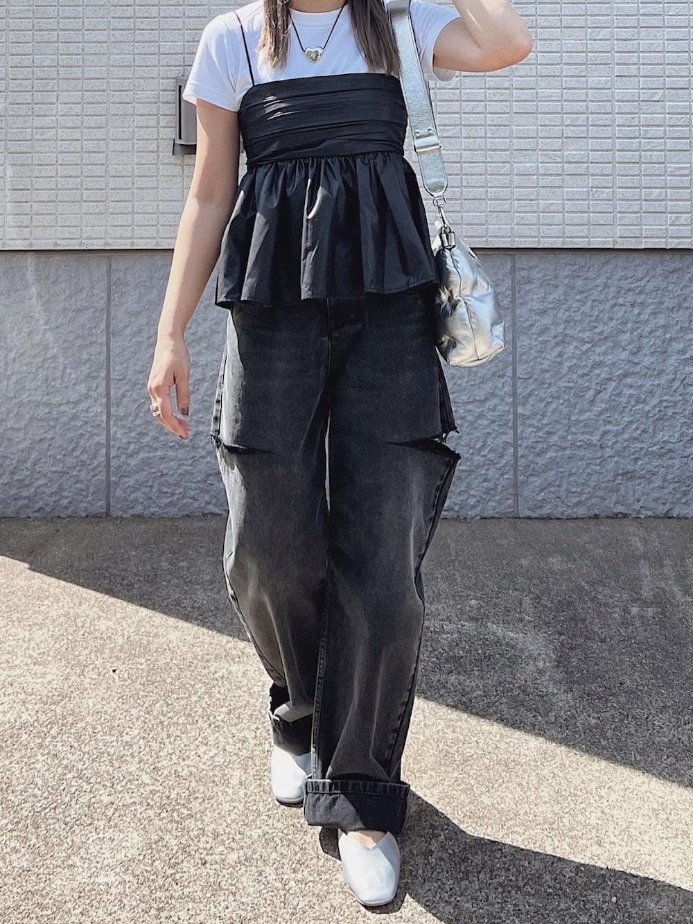 シルバー系のパンプス、ブラック系のデニムパンツ、ブラック系のキャミソールを着用したレディースの秋コーディネートの2枚目の写真