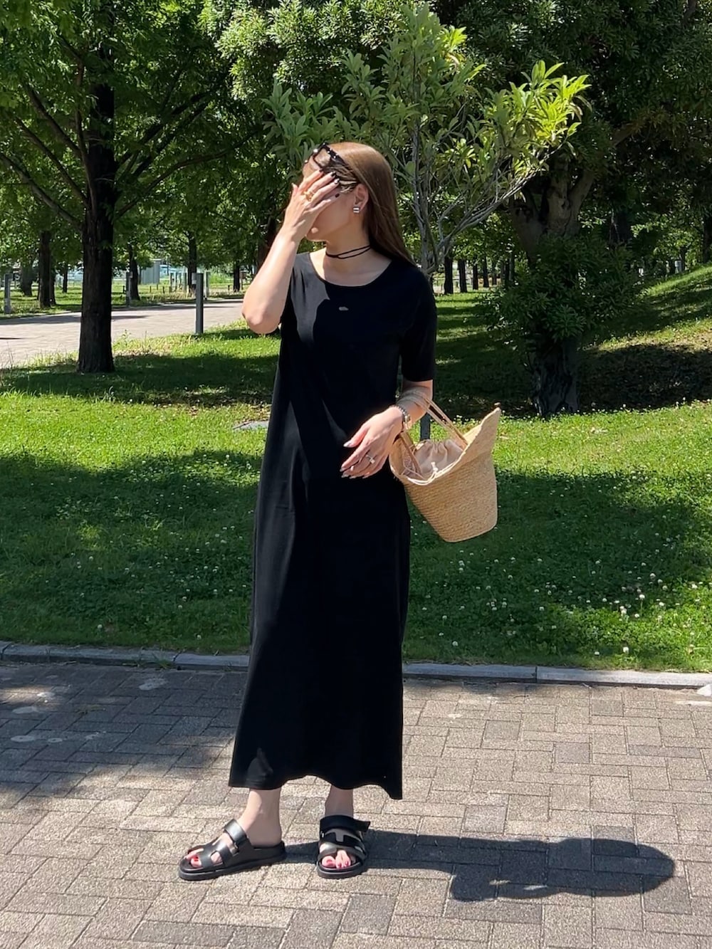 ブラック系のワンピース、ベージュ系のかごバッグ、ブラック系のサンダルを着用したレディースの夏コーディネートの4枚目の写真